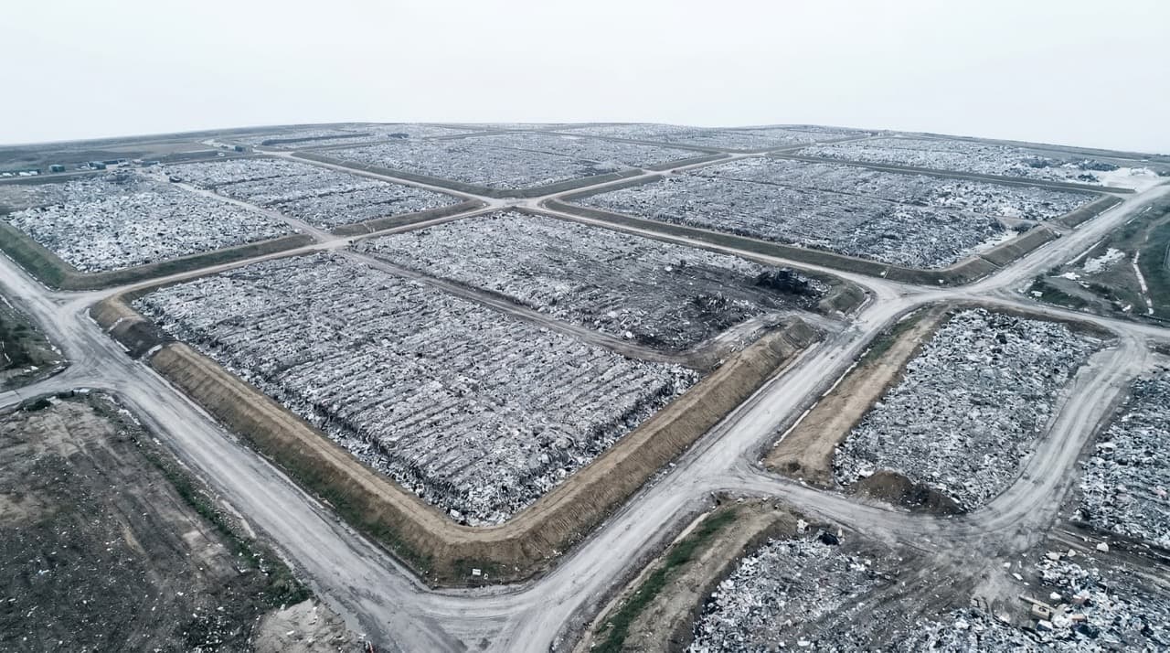 Aerial view of a UK landfill site showing compressed waste cells and access tracks — UK operators currently pay £130.75 per tonne in standard landfill tax, a cost that can be eliminated entirely through on-site subcritical water hydrolysis treatment