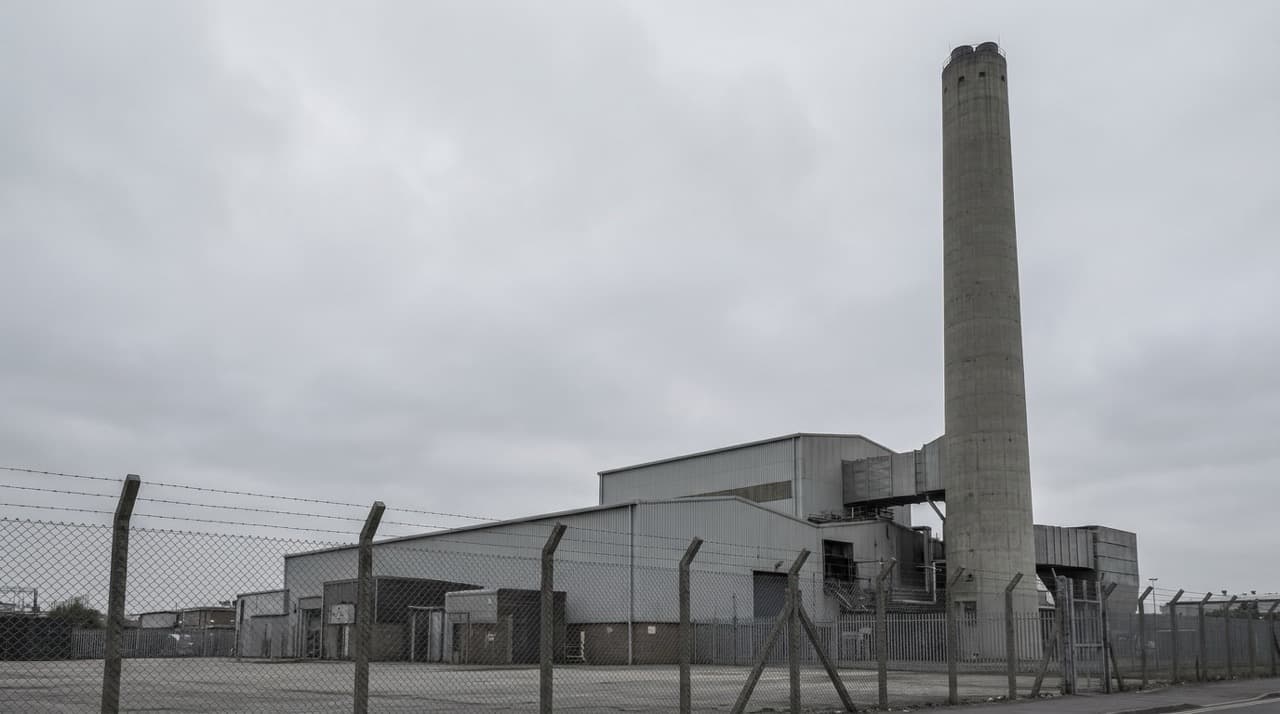 Exterior of an industrial waste incineration facility with concrete chimney stack and corrugated processing building — representing the capital cost, permitting burden, and EU ETS carbon liability PHANTOM avoids