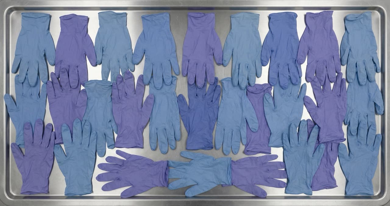 Large quantity of discarded nitrile examination gloves — visualising unnecessary glove consumption in hospital settings where WHO now recommends hand hygiene over routine glove use